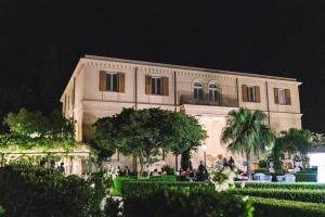 Villa Pulejo في مسينة: مبنى ابيض كبير امامه اشجار