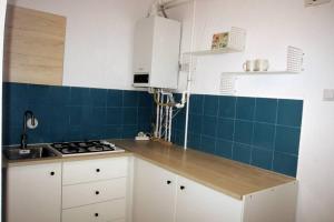 une cuisine avec des placards blancs et du carrelage bleu sur le mur. dans l'établissement SMB Studio Poarta Schei, à Braşov