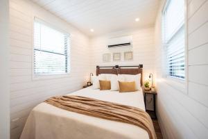a bedroom with a large bed in a white room at The Newtonian Tiny Container Home near Magnolia in Bellmead