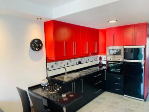 コティージョにあるAtlantic Green 3の赤いキャビネットと黒いカウンター付きのキッチン