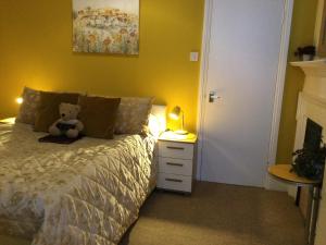 a teddy bear sitting on a bed in a bedroom at Arun Sands Rooms in Littlehampton