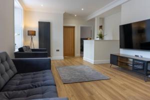 a living room with a couch and a flat screen tv at Argyle Square Apartment in Oban