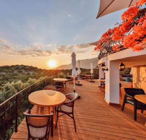 a balcony with tables and chairs and the sunset at Hill House Adult Only in Kaş