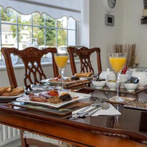 una mesa con platos de comida y vasos de zumo de naranja en Woodleigh Lodge, en Gorey