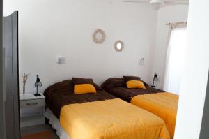 2 camas en un dormitorio con almohadas amarillas en Mono ambiente amplio, luminoso y moderno con excelente ubicación, en Rafaela