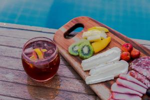 a wooden cutting board with cheese and fruit and a drink at Diff Hotel in Rio Branco