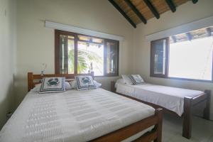 two beds in a room with two windows at Sal Si Puedes in Tintipan Island