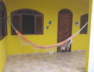 une maison jaune avec un filet suspendu à un mur dans l'établissement Casa para temporada em Rio das Ostras, à Rio das Ostras