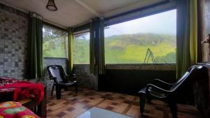 a bedroom with a large window with a view of a mountain at The Butterfly cottage Vagamon in Vagamon