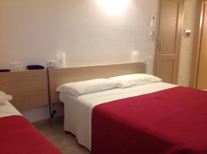 a hotel room with a bed with a red blanket at Albergo La Portaccia in Castiglione della Pescaia