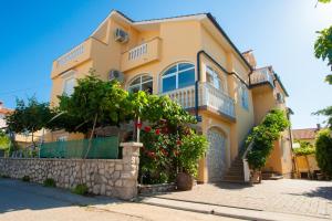a yellow house with trees and flowers in front of it at Pansion Tina in Šilo