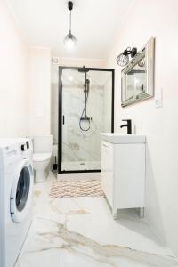 a white bathroom with a washing machine and a sink at Apartament Uroczy in Legnica