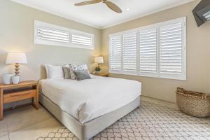 a bedroom with a bed and a window with shutters at Serenity on Hastings Street, Noosa Heads in Noosa Heads