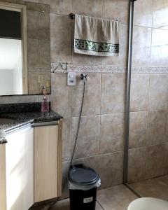 a bathroom with a shower with a trash can at Quarto Privado em residência no Coração de Foz - casa e banheiro compartilhado in Foz do Iguaçu