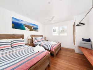 Duas camas num quarto com paredes brancas e pisos de madeira em Shoal Bay Views em Shoal Bay
