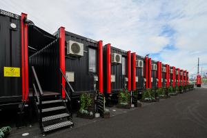 una fila di container di trasporto di colore nero e rosso con piante di HOTEL R9 The Yard Tsuyama a Tuyama