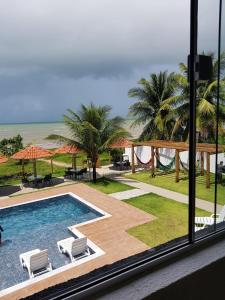 a view of a swimming pool with chairs and the ocean at Condomínio Praias de Maragogi & Casas Deluxe in Maragogi