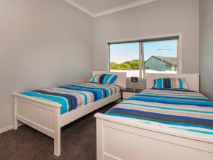 2 camas en una habitación blanca con ventana en Hosts on the Coast Belair Bach en Whitianga