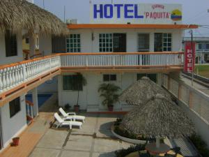 a hotel with chairs and umbrellas in front of it at Hotel QP in Chachalacas