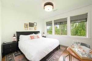 a bedroom with a bed and a table and windows at The Setting Inn Willamette Valley in Newberg