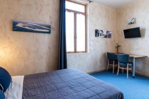 a bedroom with a bed and a table and a window at H&ocirc;tel de la Gare in Latresne