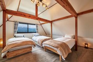 three beds in a room with a window at Sunnsnow Tall house in Nagano