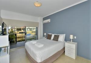 a bedroom with a white bed and a balcony at DelMar 3 in Mandurah