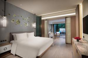 a bedroom with a large white bed and a living room at Crowne Plaza Shanghai Nanjing Road by IHG in Shanghai