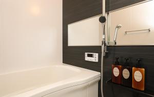 a bathroom with a white tub and a white toilet at GRAND BASE Hakataminami in Fukuoka