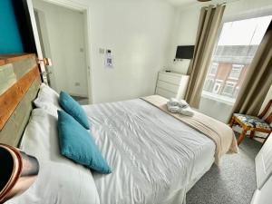 a bedroom with a bed with blue pillows and a window at The Corner House - Modern Chesterfield Town Centre Apartments in Chesterfield