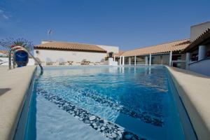 a swimming pool in a villa with blue water at Le Maset en Camargue in Saintes-Maries-de-la-Mer