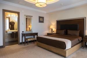 1 dormitorio con cama, escritorio y espejo en Chinar Hotel & Spa Naftalan, en Naftalan