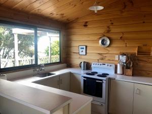 eine Küche mit einem Herd und einem Fenster in einer Hütte in der Unterkunft Bay View Bach in Raglan