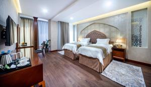 ein Hotelzimmer mit 2 Betten und einem TV in der Unterkunft Manor Hotel in Taschkent