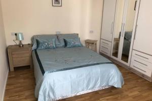 a bedroom with a bed with blue pillows and a mirror at Guest house in the New Forest near Paulton's Park in Cadnam