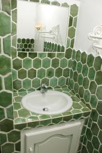 ein grün gefliestes Bad mit einem Waschbecken und einem Spiegel in der Unterkunft Saint Joseph in Grimaud