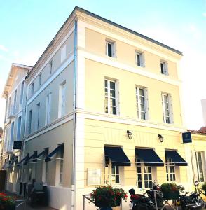 un gran edificio blanco con toldos negros. en Hôtel Restaurant Le Galet Bleu, en Fouras