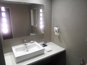 y baño con lavabo blanco y espejo. en Minerva Grand Kondapur, en Hyderabad