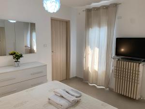 a white bedroom with a television and towels on a bed at La Spolina B&B in Cossato
