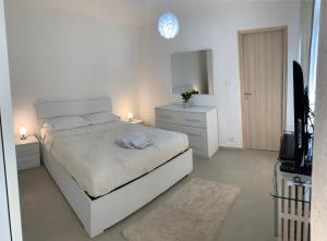 a white bedroom with a bed and a television at La Spolina B&B in Cossato