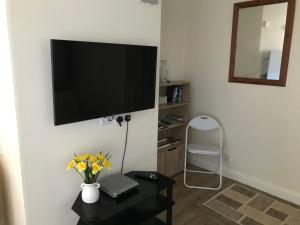 uma sala de estar com uma televisão de ecrã plano na parede em Sea Shells em Greatstone