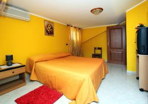 1 dormitorio con cama y pared amarilla en Bed and Breakfast Vibo Mare, en Vibo Valentia Marina