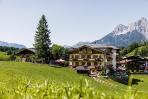 a building on a hill with mountains in the background at Hotel Langeck in Maria Alm am Steinernen Meer