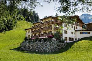 a large building on a hill with a stone wall at Hotel Langeck in Maria Alm am Steinernen Meer