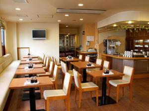 a restaurant with wooden tables and chairs and a kitchen at Hotel Ohta in Ōzu