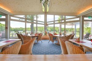 a dining room with tables and chairs and windows at Emsland Hotel Saller See in Freren