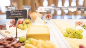 a table with cheese and grapes and other foods at JUFA Hotel Hochrindl in Hochrindl