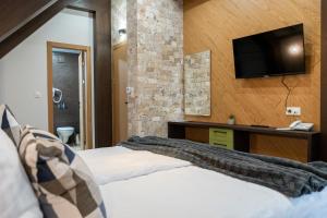 ein Schlafzimmer mit einem Bett und einem TV an der Wand in der Unterkunft 103 Alpine Hotel in Panichishte