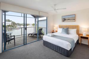 a bedroom with a bed and a balcony at Captains Cove Resort - Waterfront Apartments in Paynesville