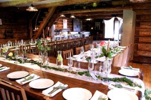 a long wooden table with white plates and napkins at Gungas in Ādaži